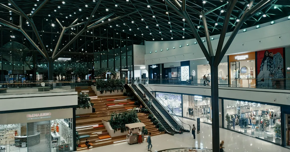 Interior amplio de un centro comercial con varios niveles y zonas de tiendas.